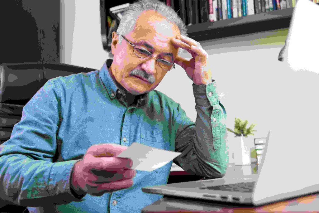 A worried man looking at his bank statement, symbolizing financial habits and money management.