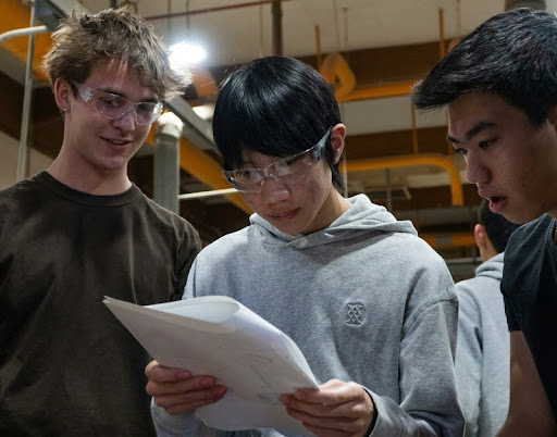 Three engineering students reviewing a document together.
