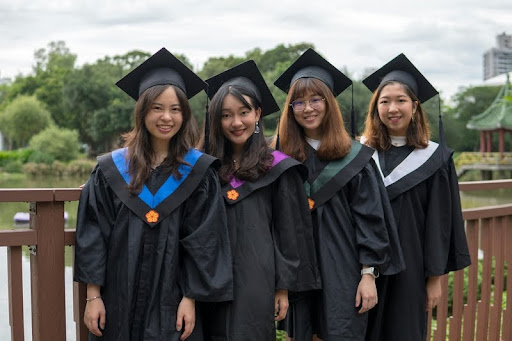 Four women in graduation gowns celebrating their achievement