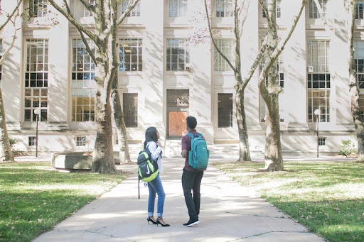 Two college students walking with backpacks on campus.