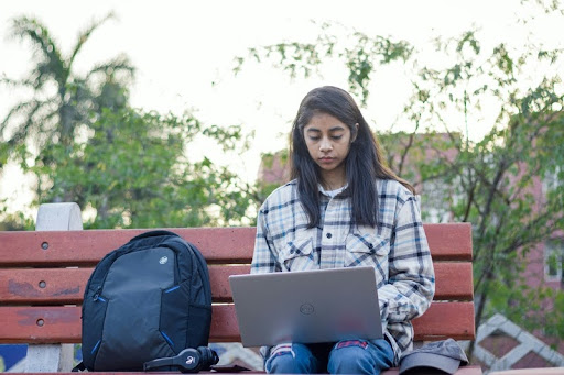 Woman sitting on a bench outside using a laptop