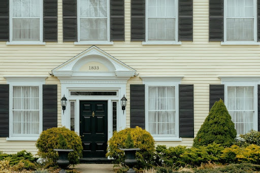 Yellow house with black shutters and a black front door