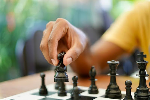 Hand holding a black and silver chess piece.