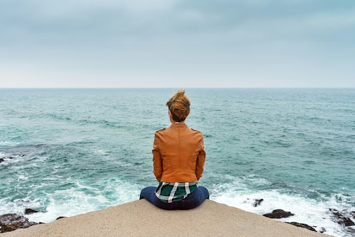 Woman sitting on a dock gazing at the ocean