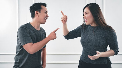 Woman visibly angry at smiling man during a tense conversation.