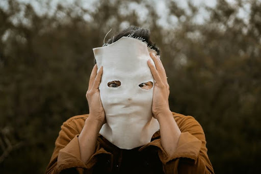 Woman standing alone wearing a face mask, symbolizing hidden emotions.
