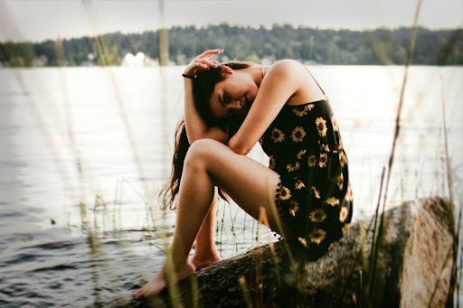 Woman sitting alone on a rock by the water