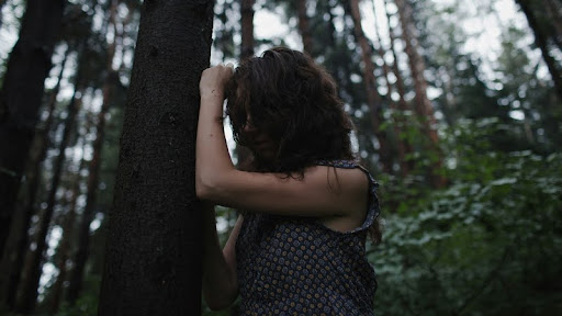 Woman standing alone in a quiet forest.