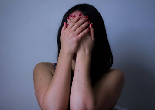 Woman covering her face with her hands, showing signs of distress or anxiety.