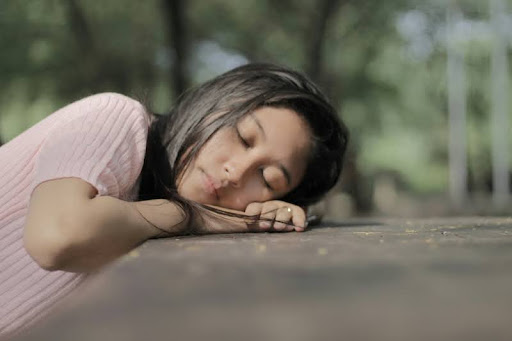 Woman sleeping with her head resting on a pavement