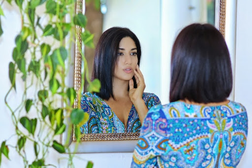 Woman looking at herself in the mirror with a thoughtful expression
