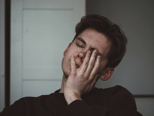 Man covering his face with his hand, looking emotionally drained.