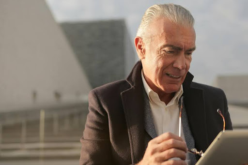 Older man holding his eyeglasses, appearing thoughtful.