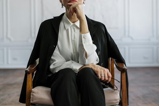 Woman in a suit sitting confidently on a wooden chair
