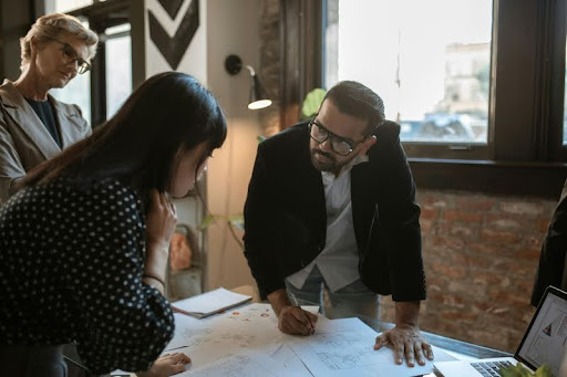 Man explaining an idea on paper to two women who are listening closely.