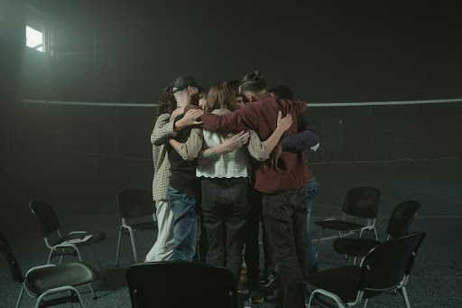 Team of colleagues hugging in a circle, showing unity and support.