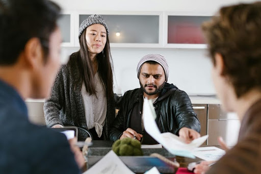 Four people sitting at a table discussing paperwork during a startup planning session.