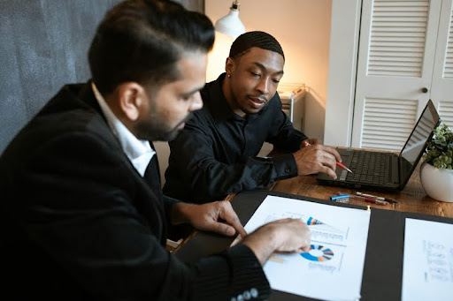 Two men discussing business strategy while using a laptop.