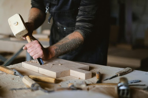 Carpenter carving wood with a chisel.