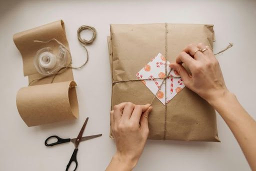 Person wrapping a package with brown kraft paper.