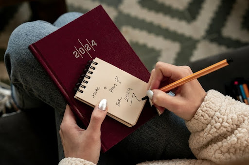 Woman’s hand holding a pen poised over a notepad.