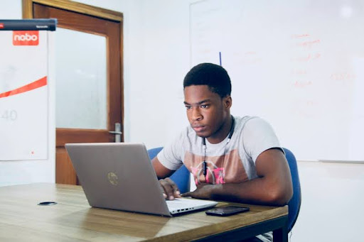 Man sitting alone in a room working on a laptop