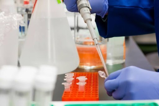 Person adding liquid to a test tube in a lab setting
