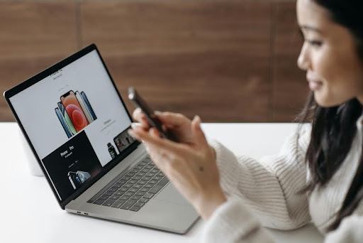 Woman using her smartphone and laptop at a table