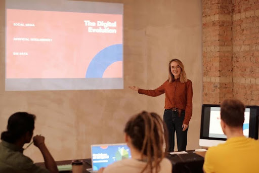 Woman presenting an AI cybersecurity concept to a group using a screen projector.