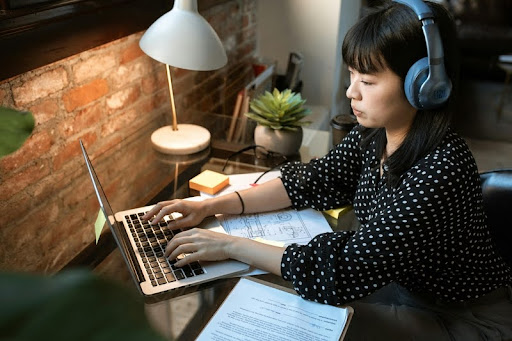 Woman wearing headphones using a laptop at home
