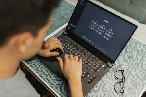 Person working on a laptop with eyeglasses and notes on the table