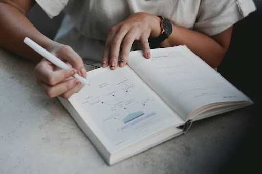 Person writing on white paper with a pen