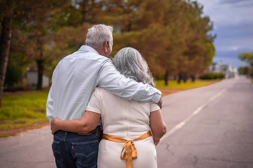 Elderly couple walking together outdoors, holding each other