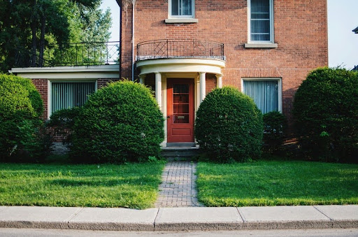 Brick house with a red front door and green lawn.