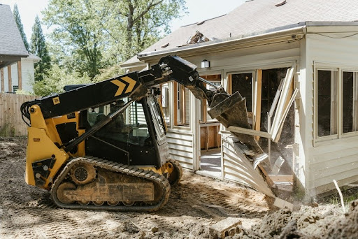 Bulldozer digging dirt in front of a residential house