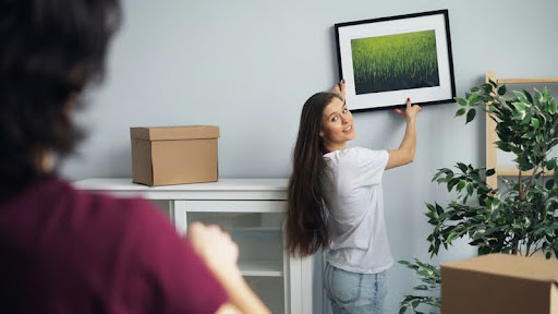 Woman hanging artwork as part of simple home staging.