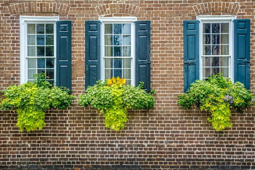 Red brick house with three windows and blue shutters