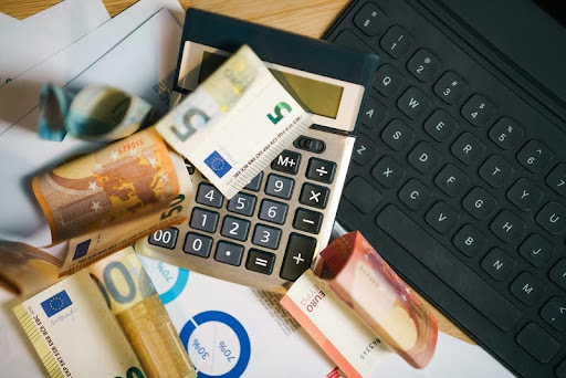 Calculator with a stack of cash, representing budgeting and cost planning