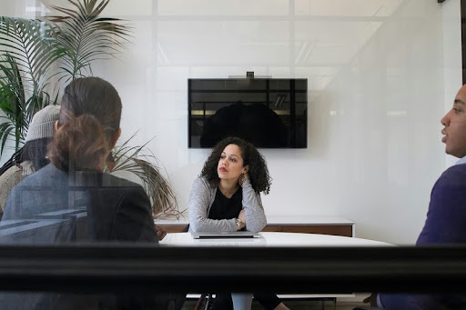 Group of coworkers sitting around a table in a modern office meeting.