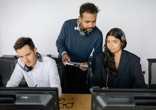 Man evaluating two employees' laptops in an office environment.