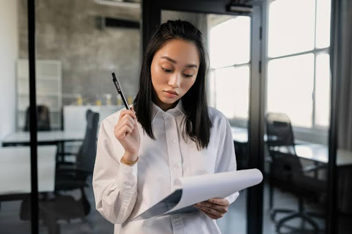 Woman reviewing notes on a clipboard with a pen in hand