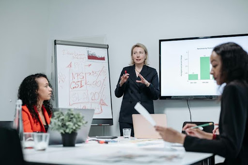 Woman in black blazer presenting during a team meeting.