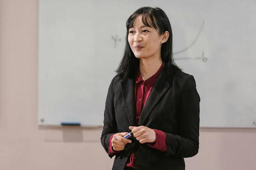 Female professional in black blazer speaking to a small group.
