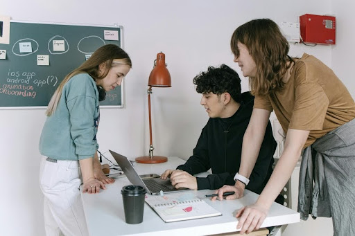 Three trainees collaborating while using a laptop during a training session.