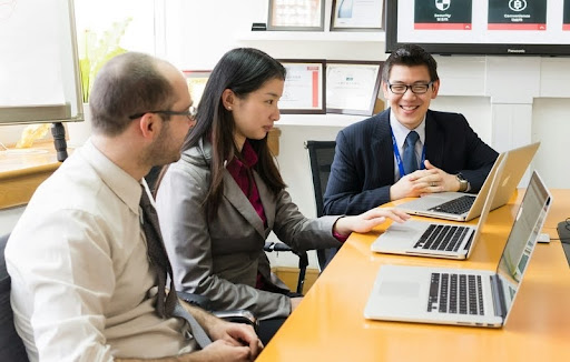 Three business professionals in suits having a serious discussion in an office.
