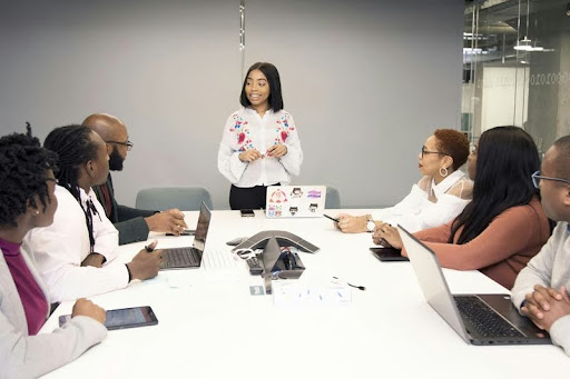 People collaborating at a round table with laptops during a team meeting.