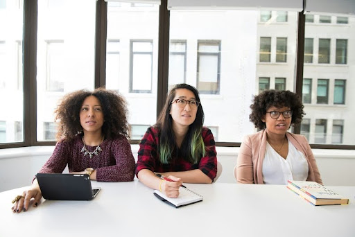 Three professional women seated at a conference table in a modern office