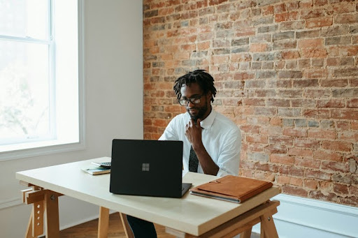 Man working on a laptop at a table in a modern workspace