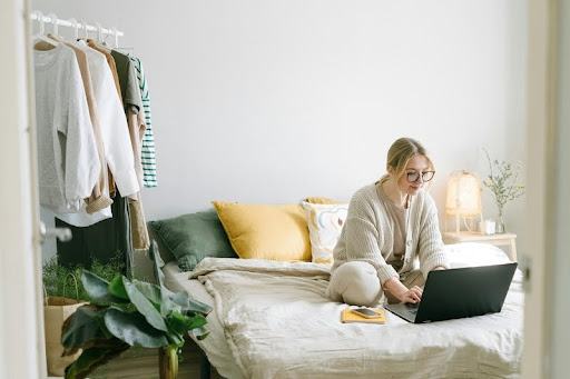 Woman working on a laptop while sitting on a bed