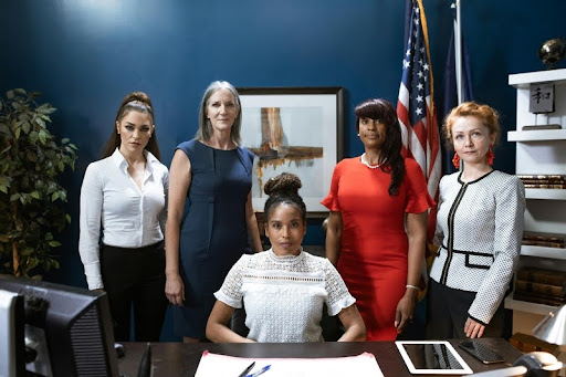 Group of diverse women standing together by an office table.